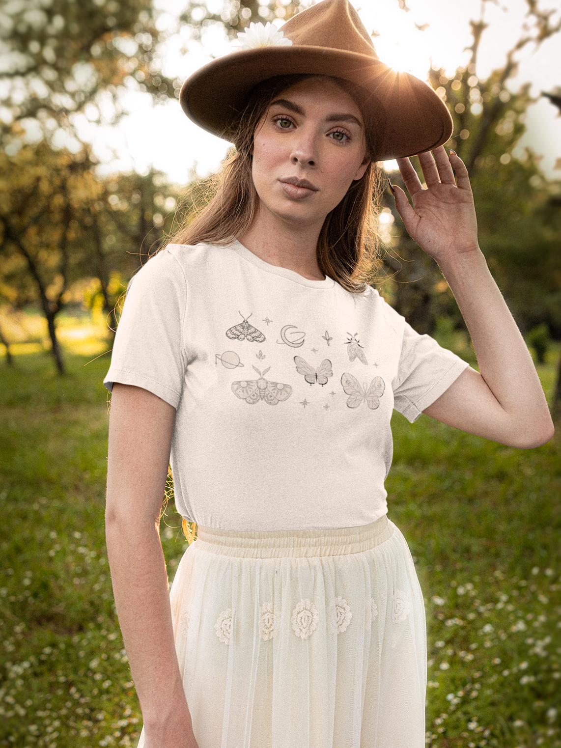 Woman wearing a white t-shirt with text and a brown hat in a natural setting